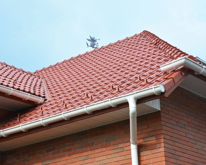 Red tiled roof with gutters on brick house.