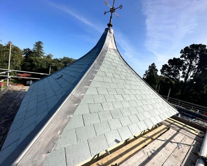 Slate roof with blue sky and weathervane.