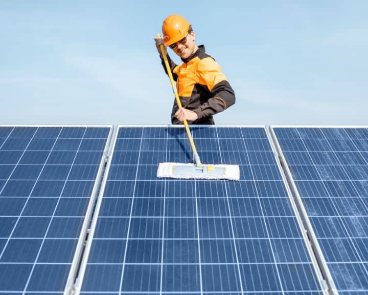 Worker cleaning solar panels outside.