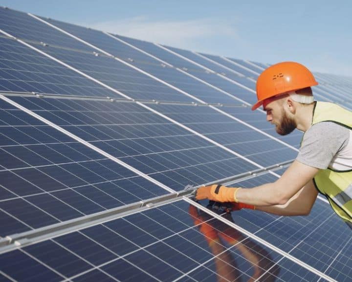 Worker installing solar panels on rooftop.
