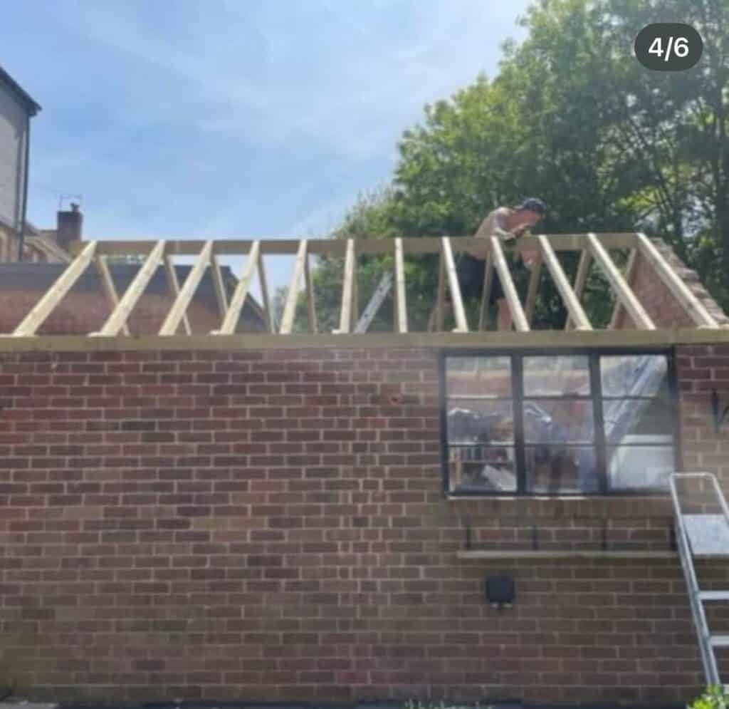 Worker building wooden roof frame on brick structure