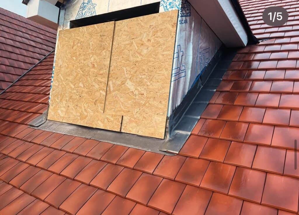 Roof tiles and unfinished dormer window on house.