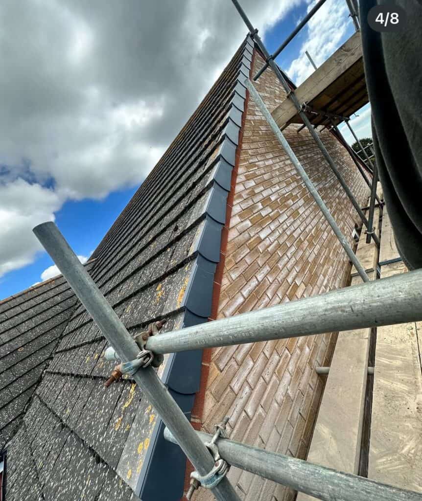 Scaffolded rooftop with grey tiles and blue sky.