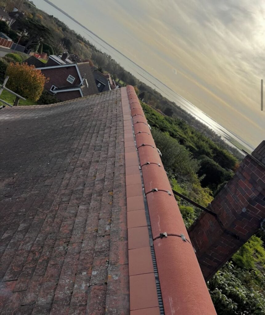 Red tiled roof with sea view and chimney.