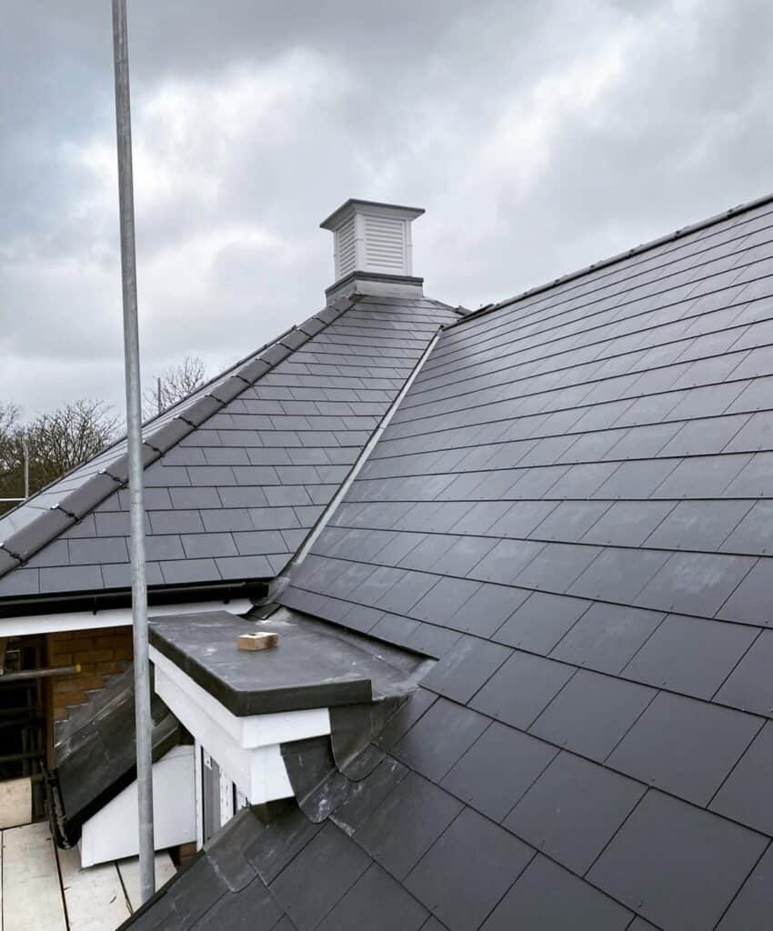 Slate roof with chimney under cloudy sky