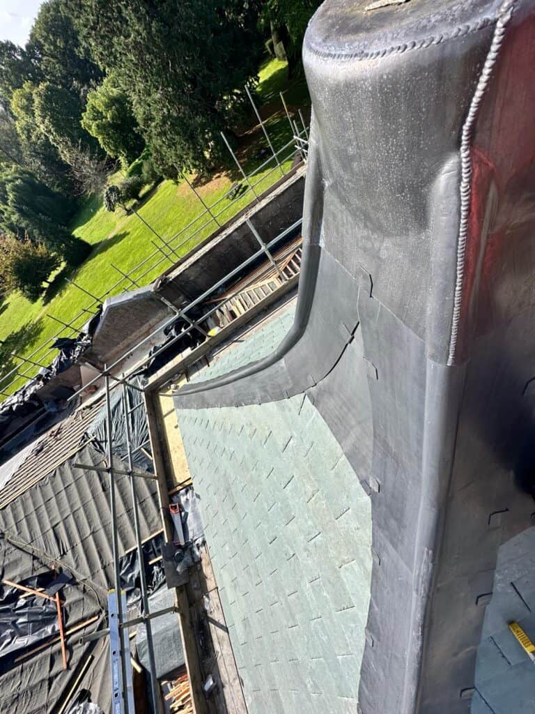 Rooftop restoration with scaffolding and surrounding greenery.