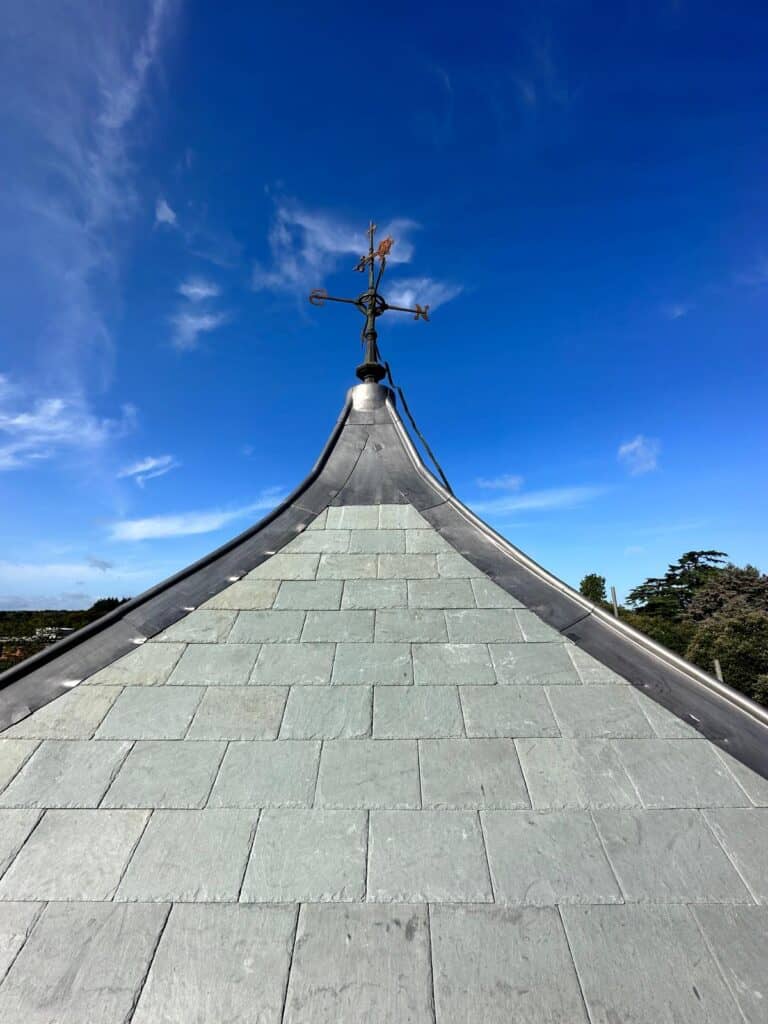 Slate roof and weather vane under blue sky