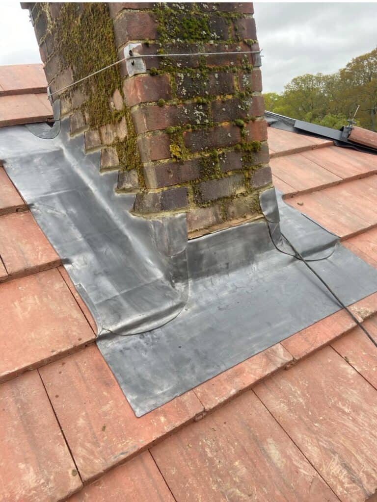 Brick chimney with moss on tiled roof