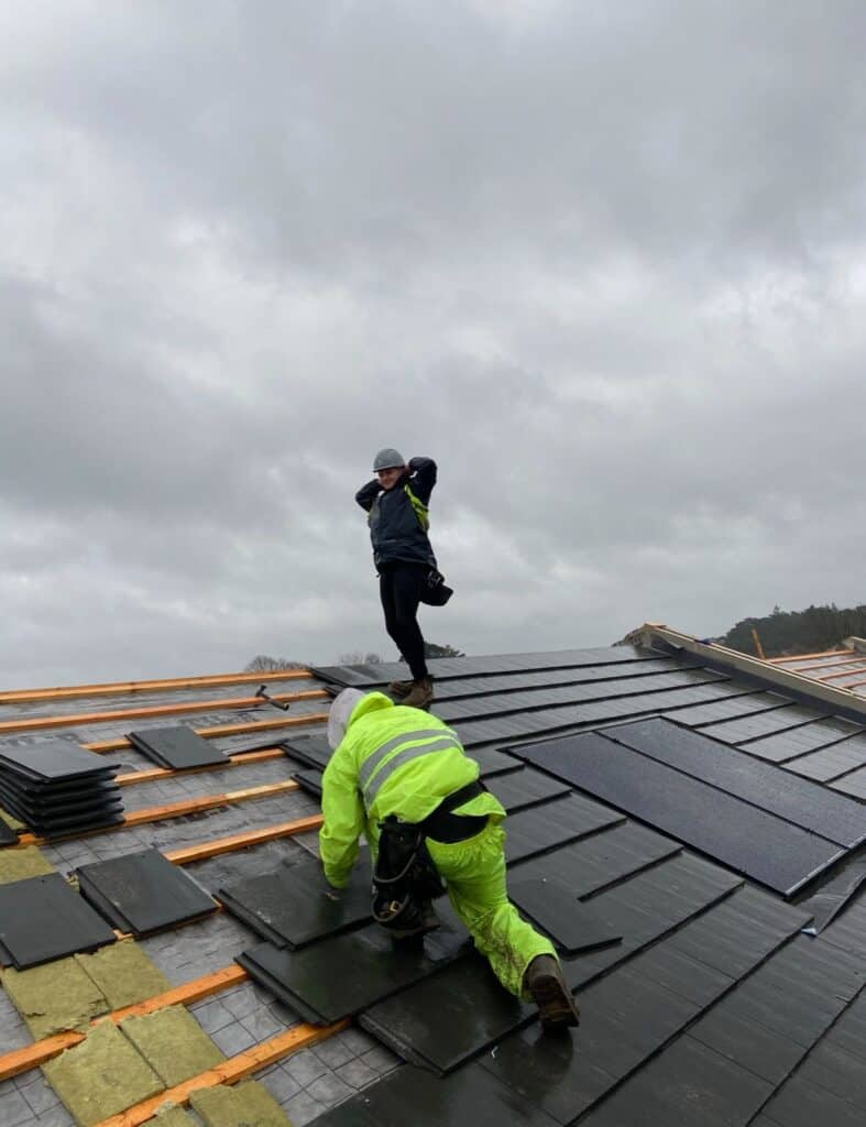 Roofers working on a tiled roof in rainy weather.