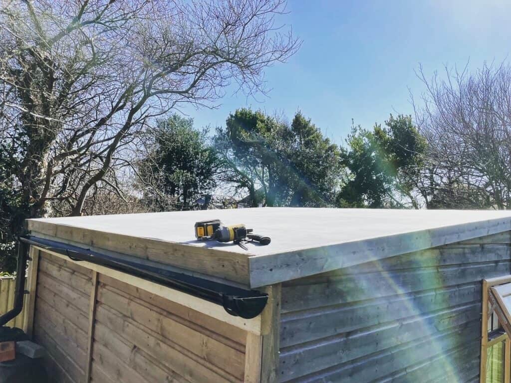 Flat wooden shed roof with tools, sunny day.
