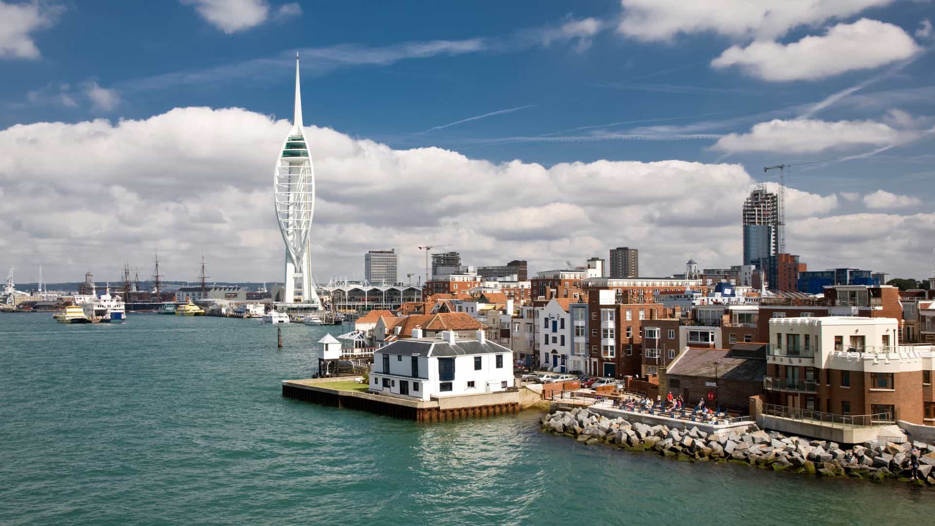 Portsmouth waterfront and Spinnaker Tower under cloudy sky.