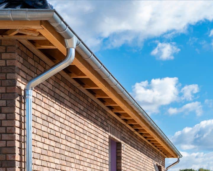 Gutters on brick house against blue sky.