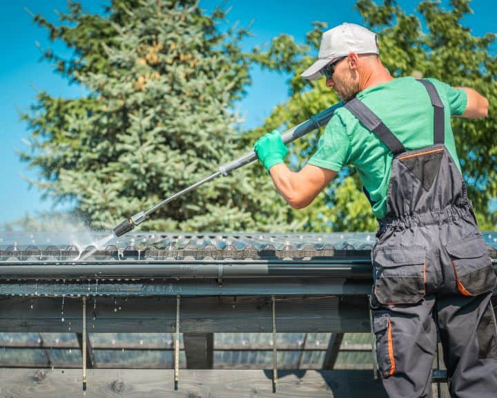 Man cleaning roof with pressure washer.
