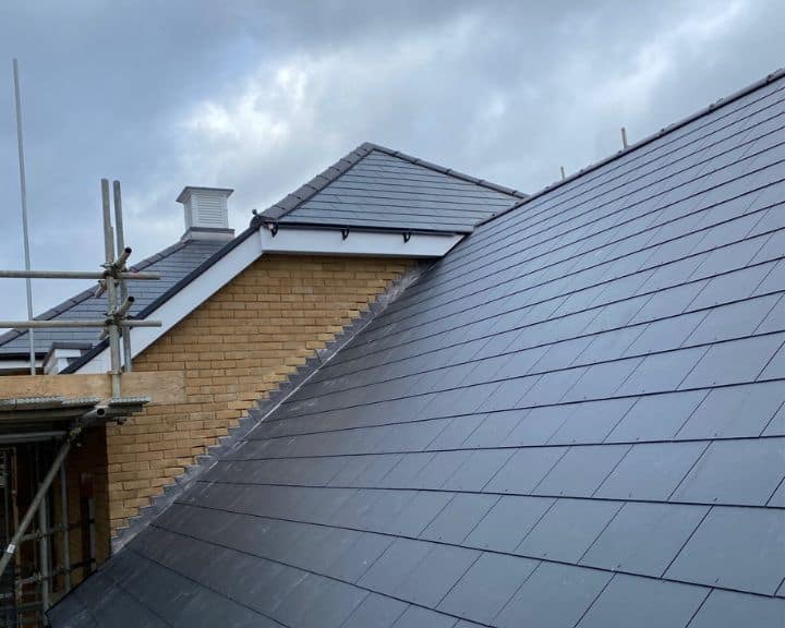 Modern slate roof with scaffolding and cloudy sky.