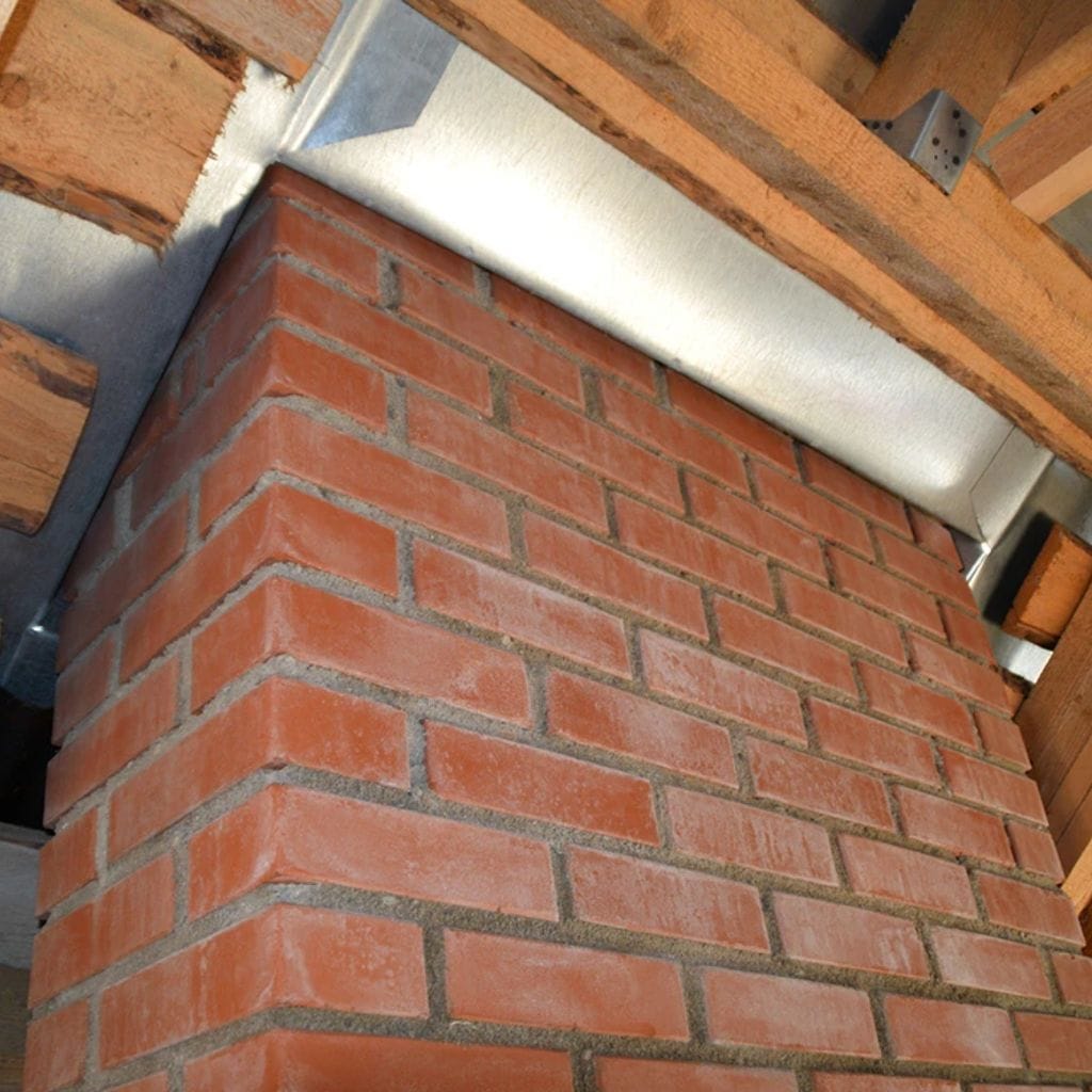 Underside of a brick chimney breast in a loft, with lead flashing meeting the timber roof rafters above.