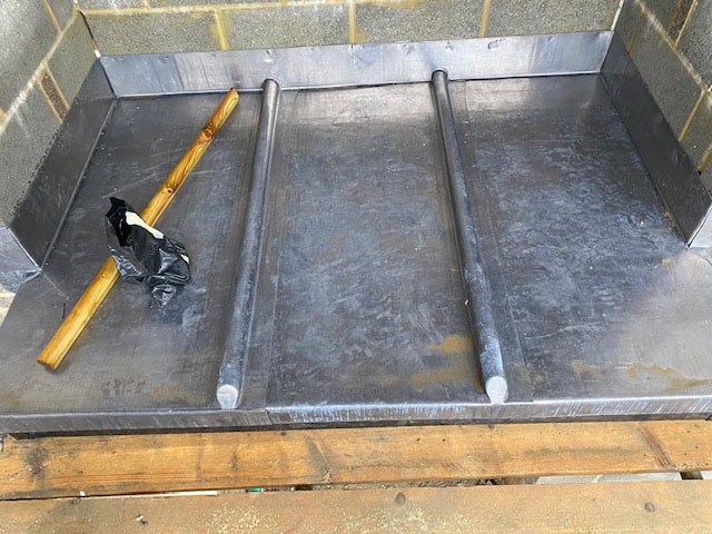 Lead-lined chimney back gutter formed against blockwork, with two rolls and a timber baton resting on the new leadwork.
