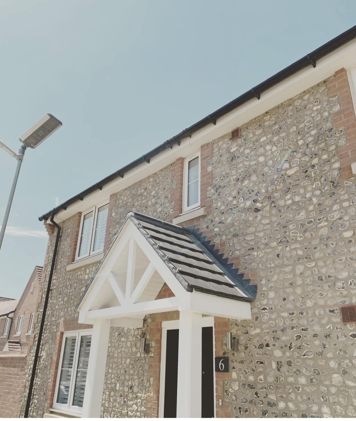 Flat felt roof topped with a red gas bottle and orange hose, edged by brick parapets above a row of houses.