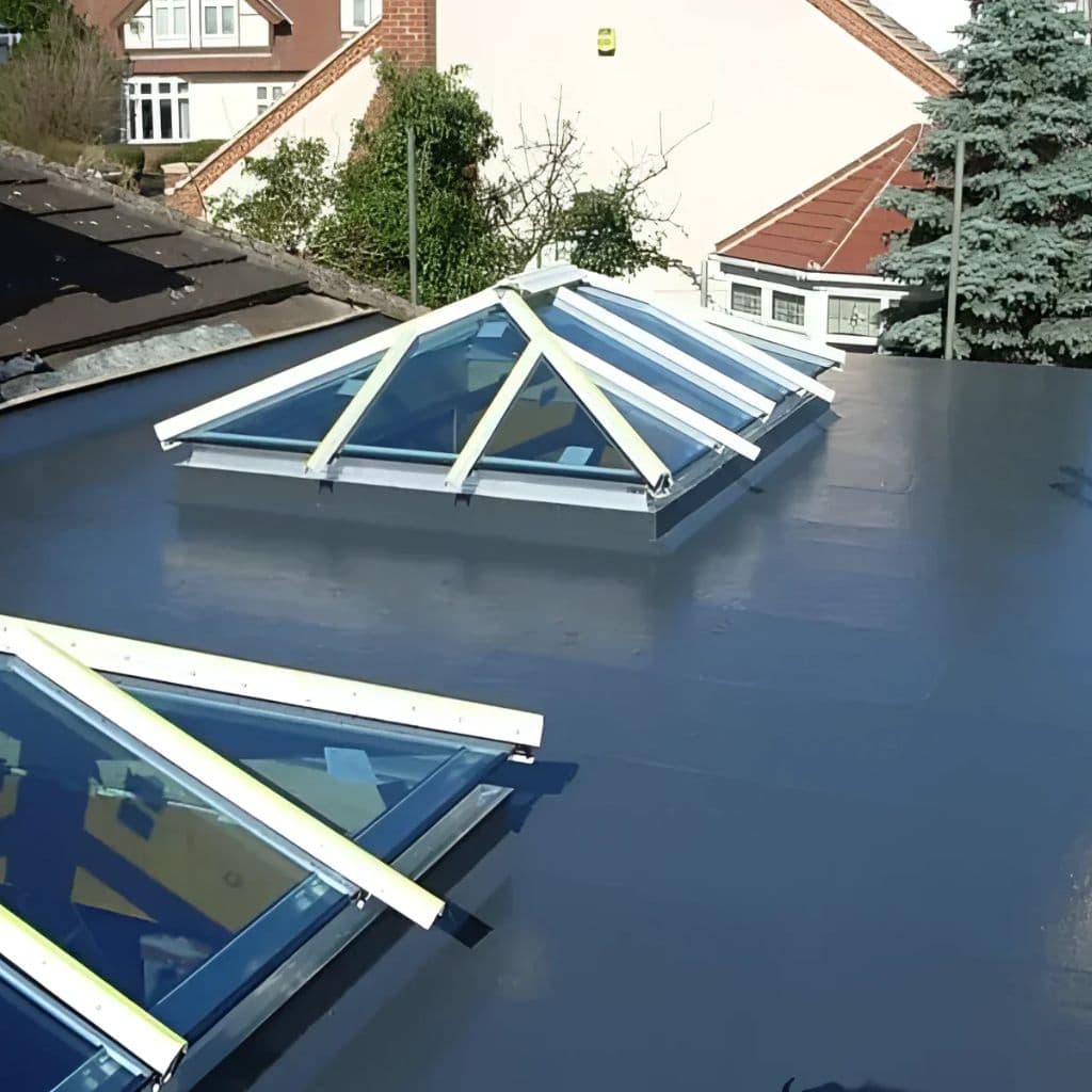Dark grey GRP flat roof with a glazed timber lantern roof and rooflights, overlooking neighbouring rooftops.