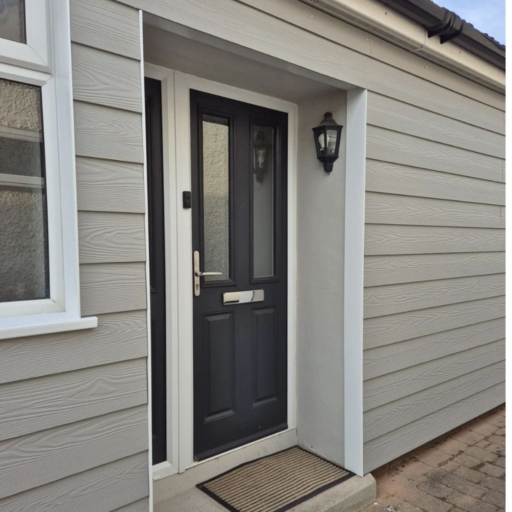 Grey fibre cement weatherboard cladding around a front porch with a dark composite door and white trims.