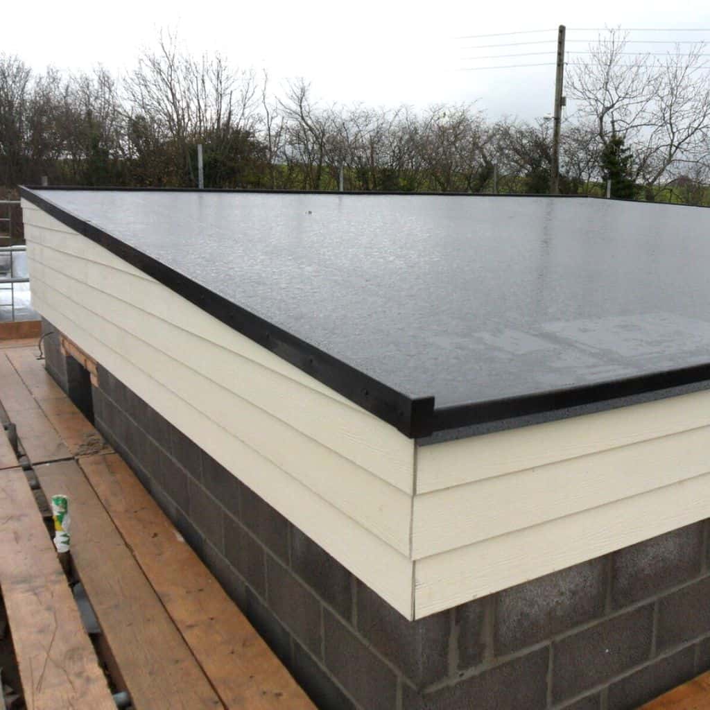 Newly installed black GRP fibreglass flat roof with raised edge trims on a building, surrounded by bare trees.