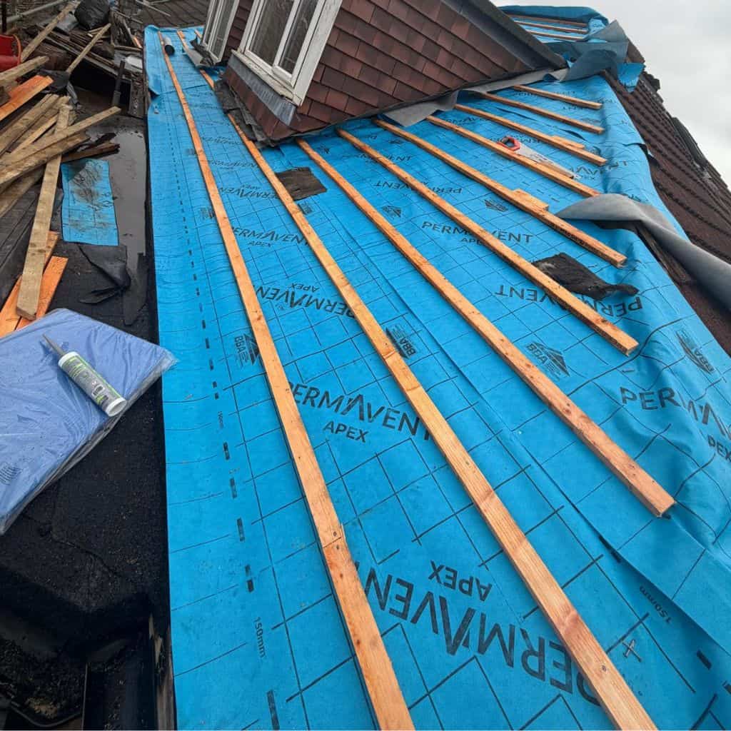 Pitched roof stripped to blue Permavent breathable underlayment with timber battens part-fitted around a dormer.