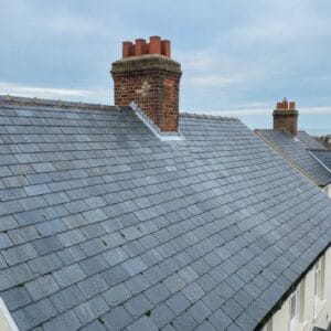 Slate tiled roof with brick chimney on a UK home.